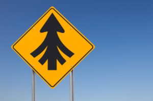 An informational traffic sign post over a clear blue sky showing that all roads lead to one